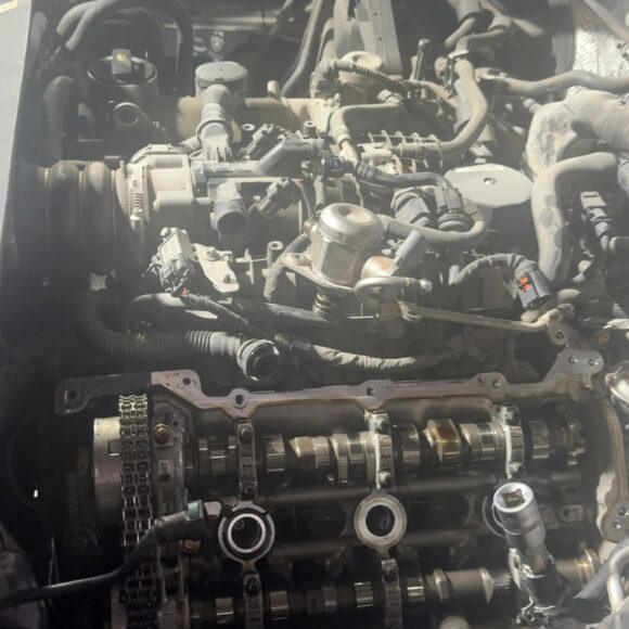 Porsche Macan engine bay with valve cover removed, showing exposed camshafts and sealing surface